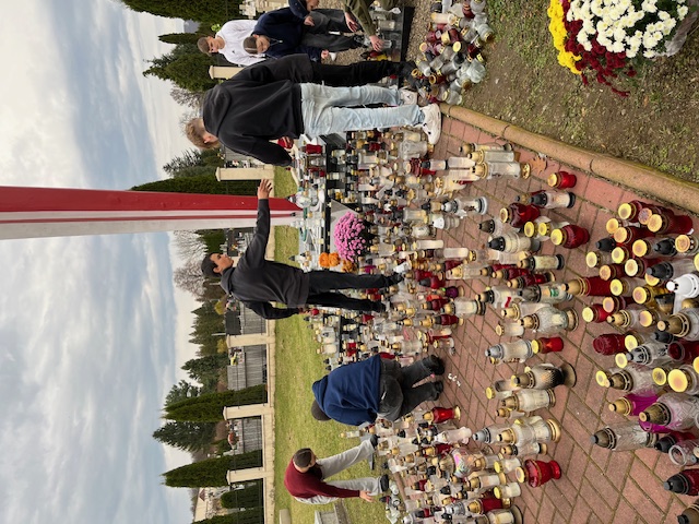 Uczniowie zapalający znicze.