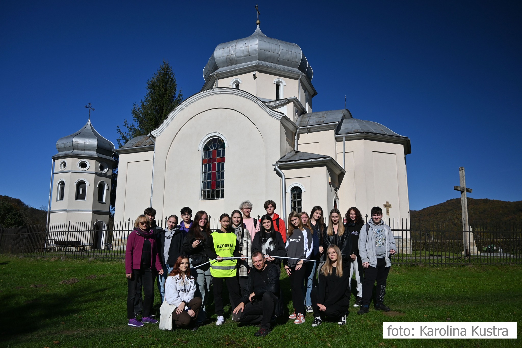 Grupa uczniów na tle cerkwi. 